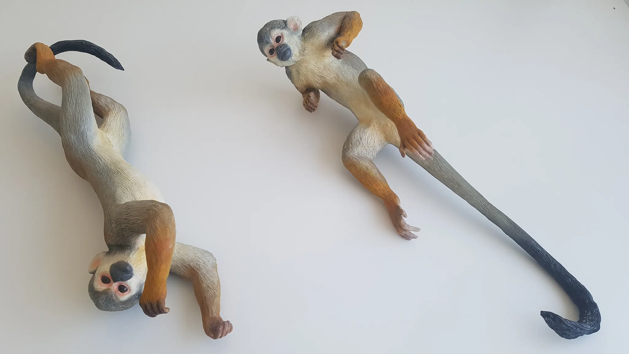 Two Saimiri sculptures arranged on a neutral surface, showing their proportions.